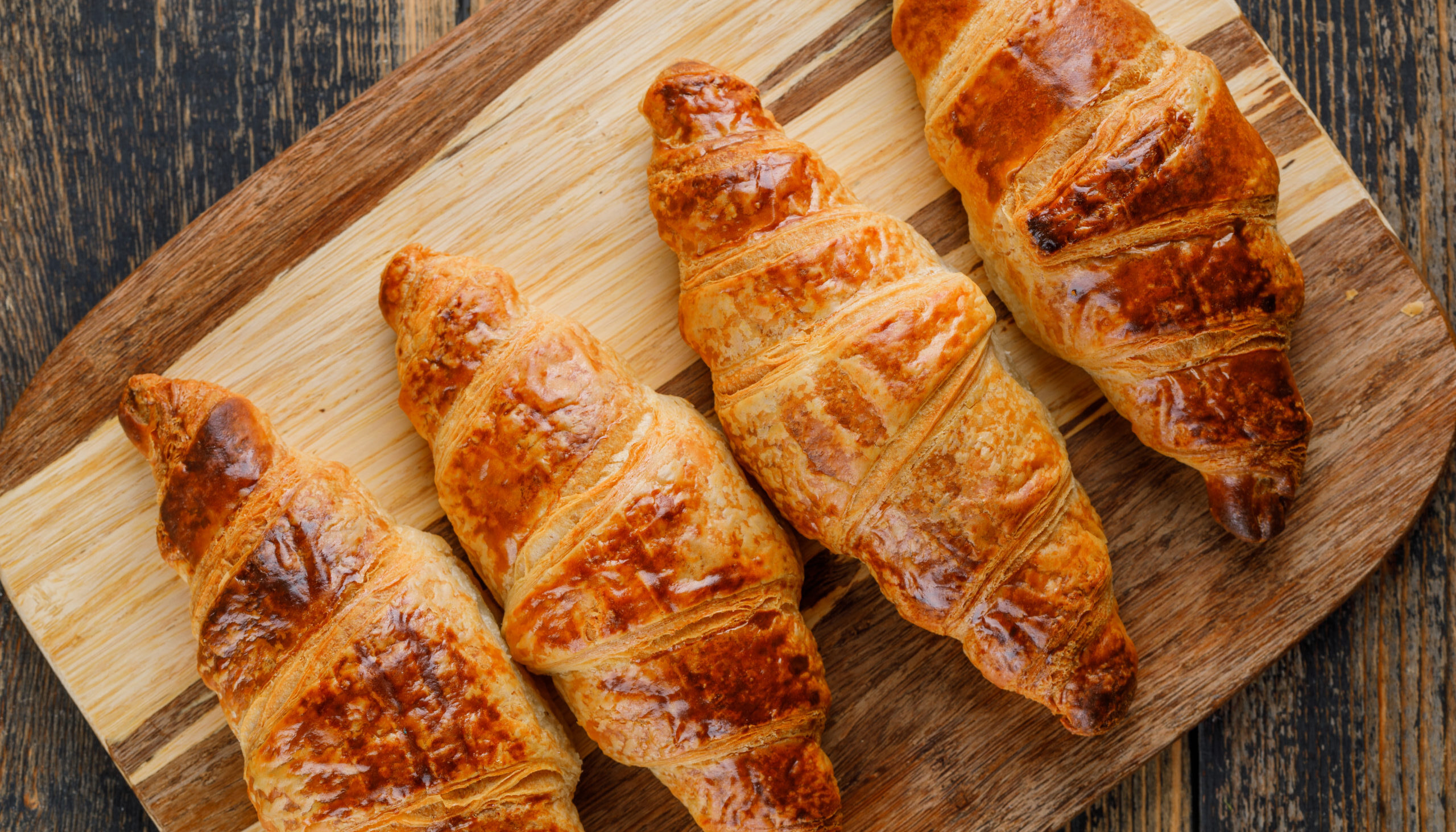 Croissant close-up on wooden and cutting board background